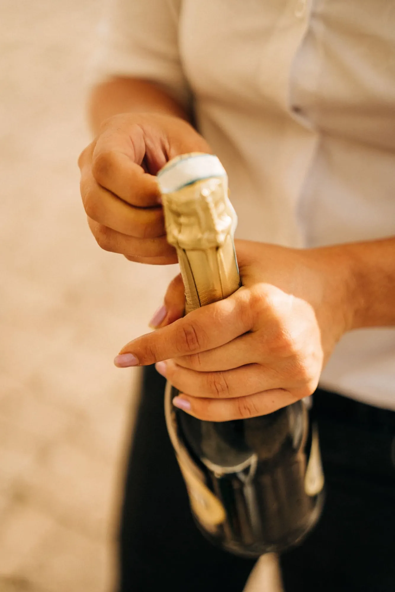 Hände öffnen eine Champagnerflasche beim Empfang