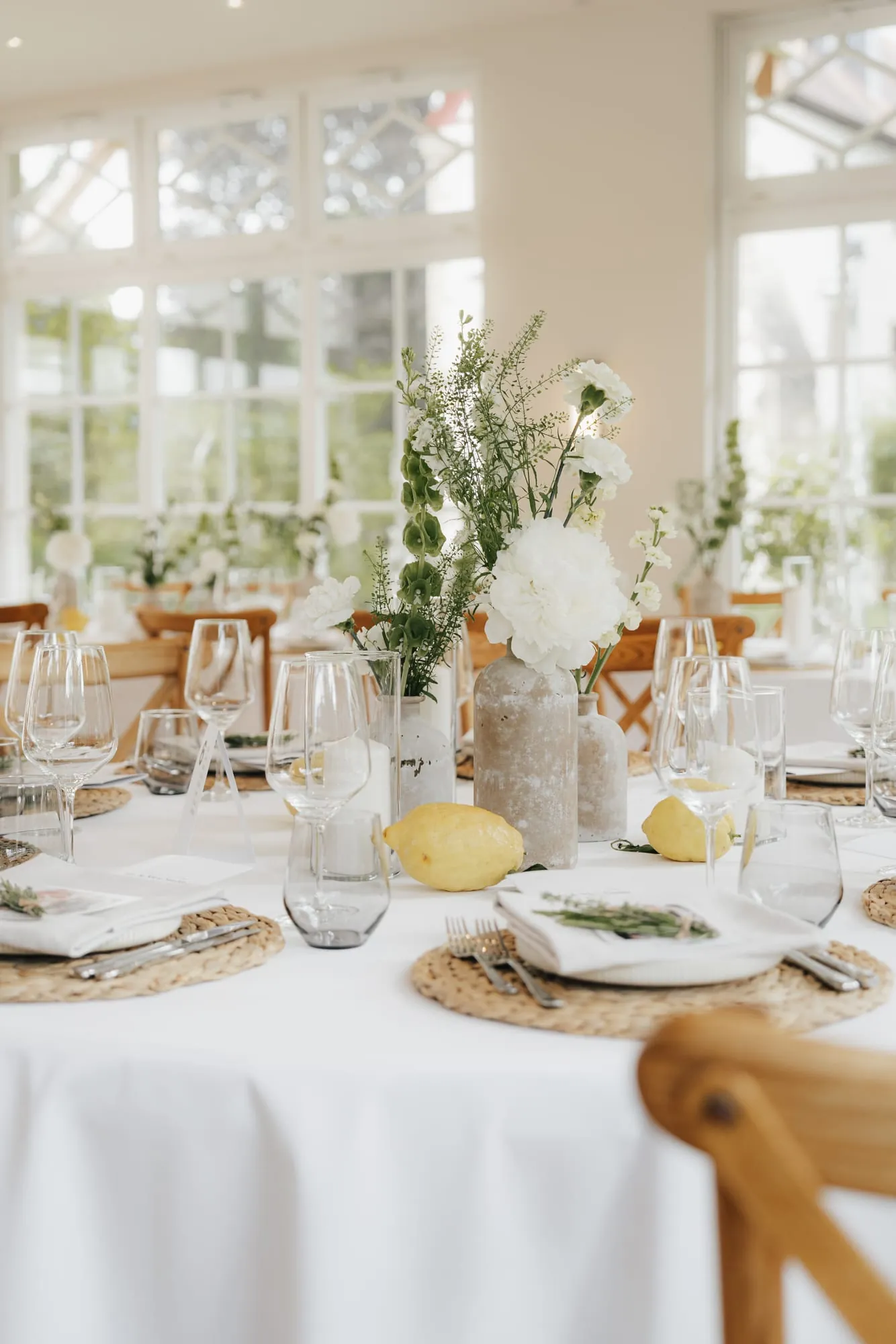 Runder Festtisch mit weißen Blumen und Zitronen im Wintergarten