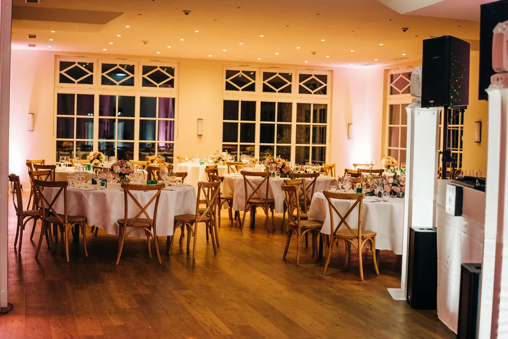 Orangerie am Abend mit runden Festtischen und Partybeleuchtung