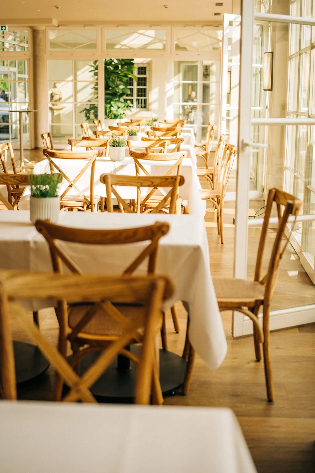 Restaurant im Wintergarten mit hellen Tischen und Blick nach draußen
