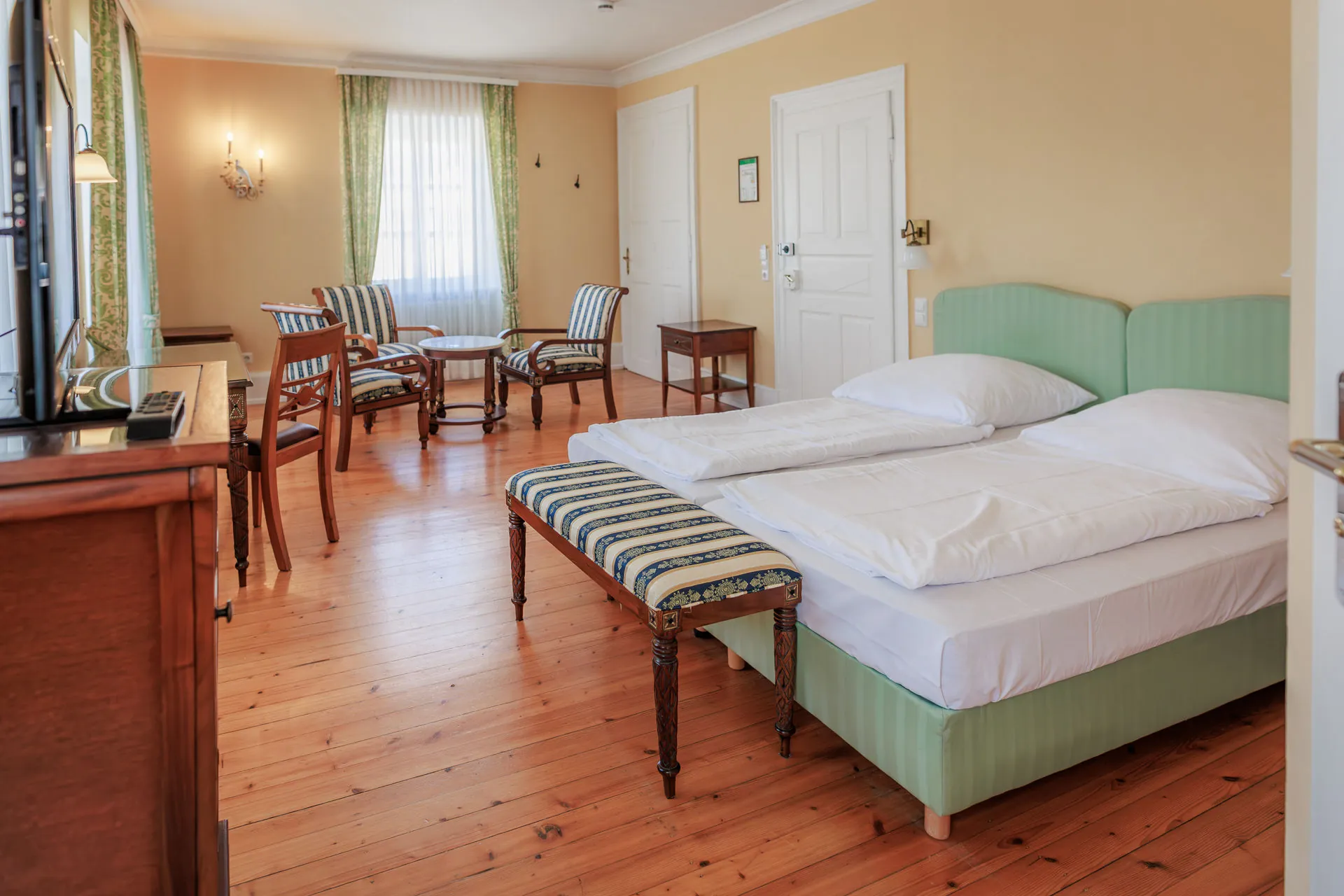 Doppelbett mit mintgrünem Kopfteil und Sitzecke im hellen Zimmer