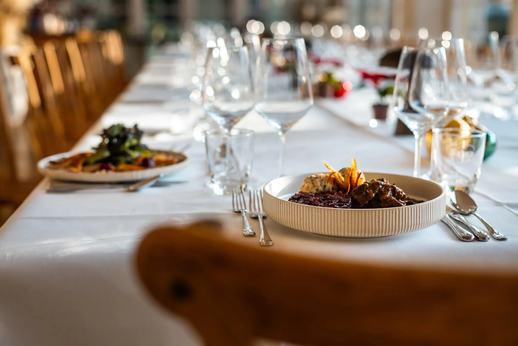 Gedeckte Tafel mit angerichteten Tellern und Gläsern