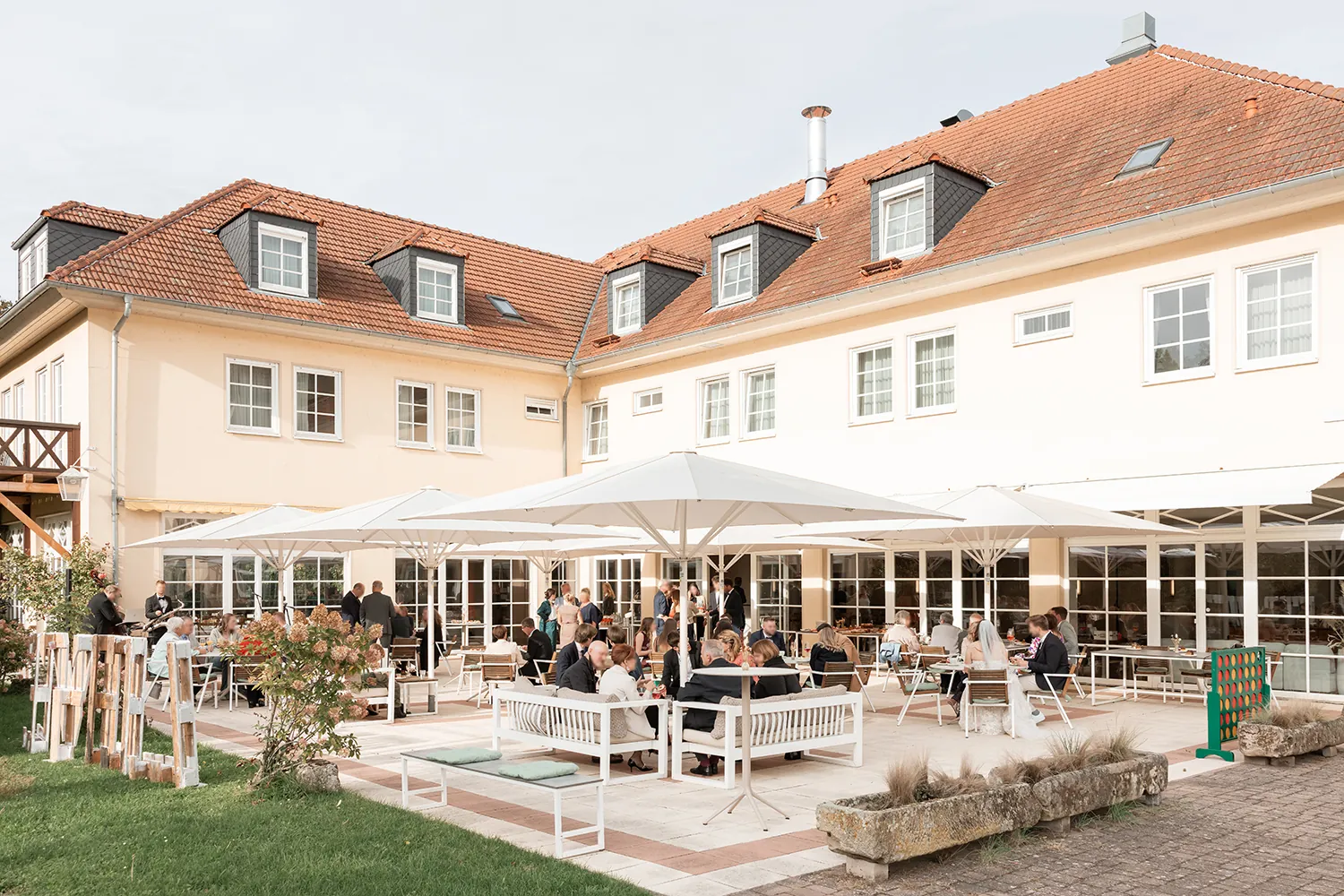 Hochzeitsgäste auf der Terrasse unter Sonnenschirmen vor dem Schlosshotel