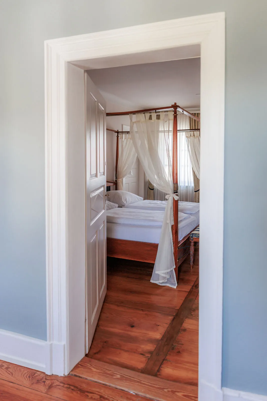 Blick durch eine offene Tür auf das Himmelbett eines Schloss-Doppelzimmers